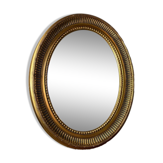 Oval-shaped wooden mirror in gold color