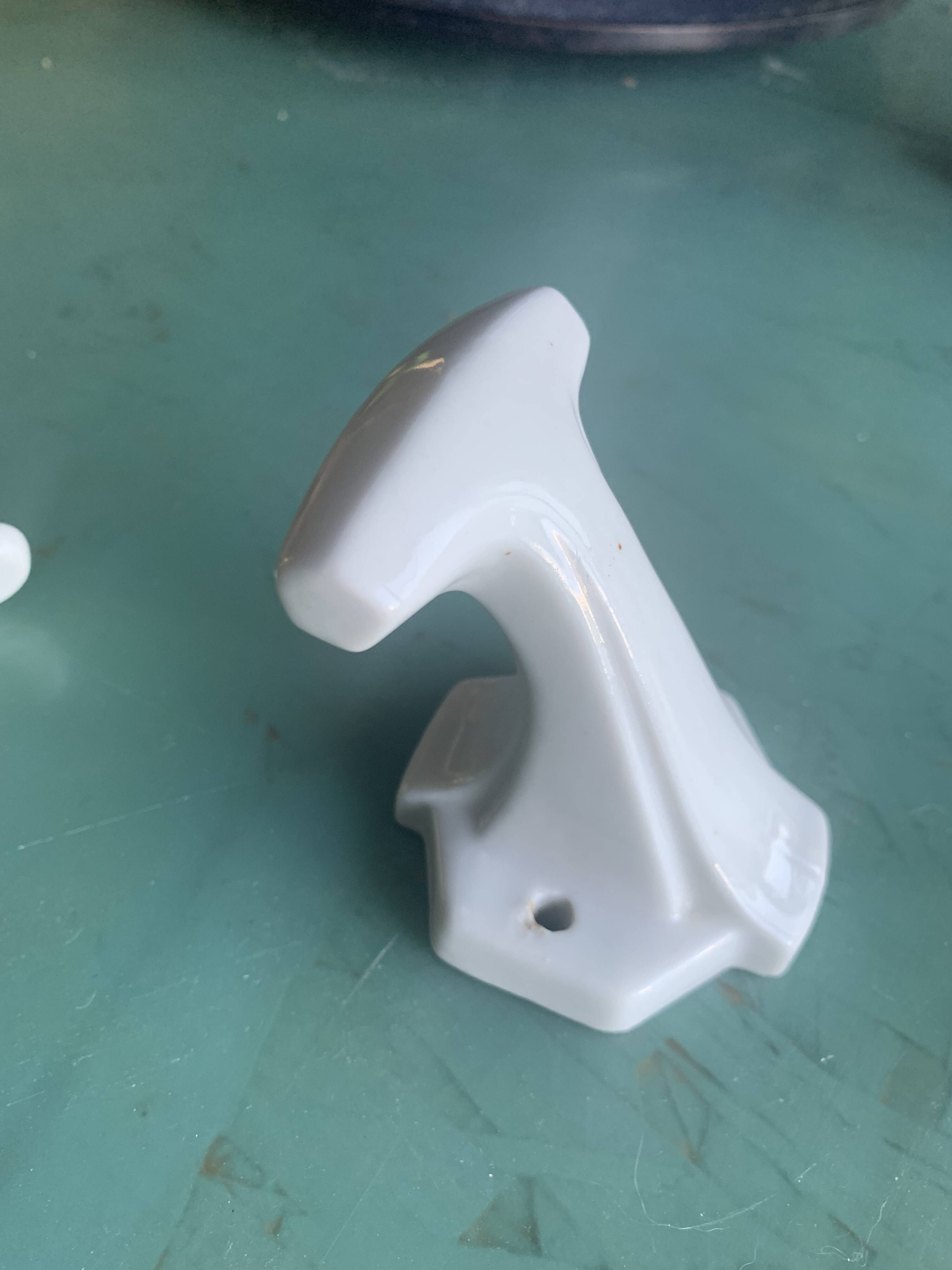 Two white porcelain coat hooks, one small and one larger, old
