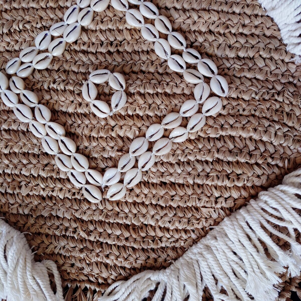 Cushion cover in natural raffia, shells and embroidery in macramé.