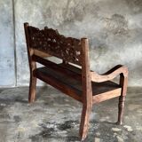 Small antique Indonesian bench in carved teak with plant and floral motifs.