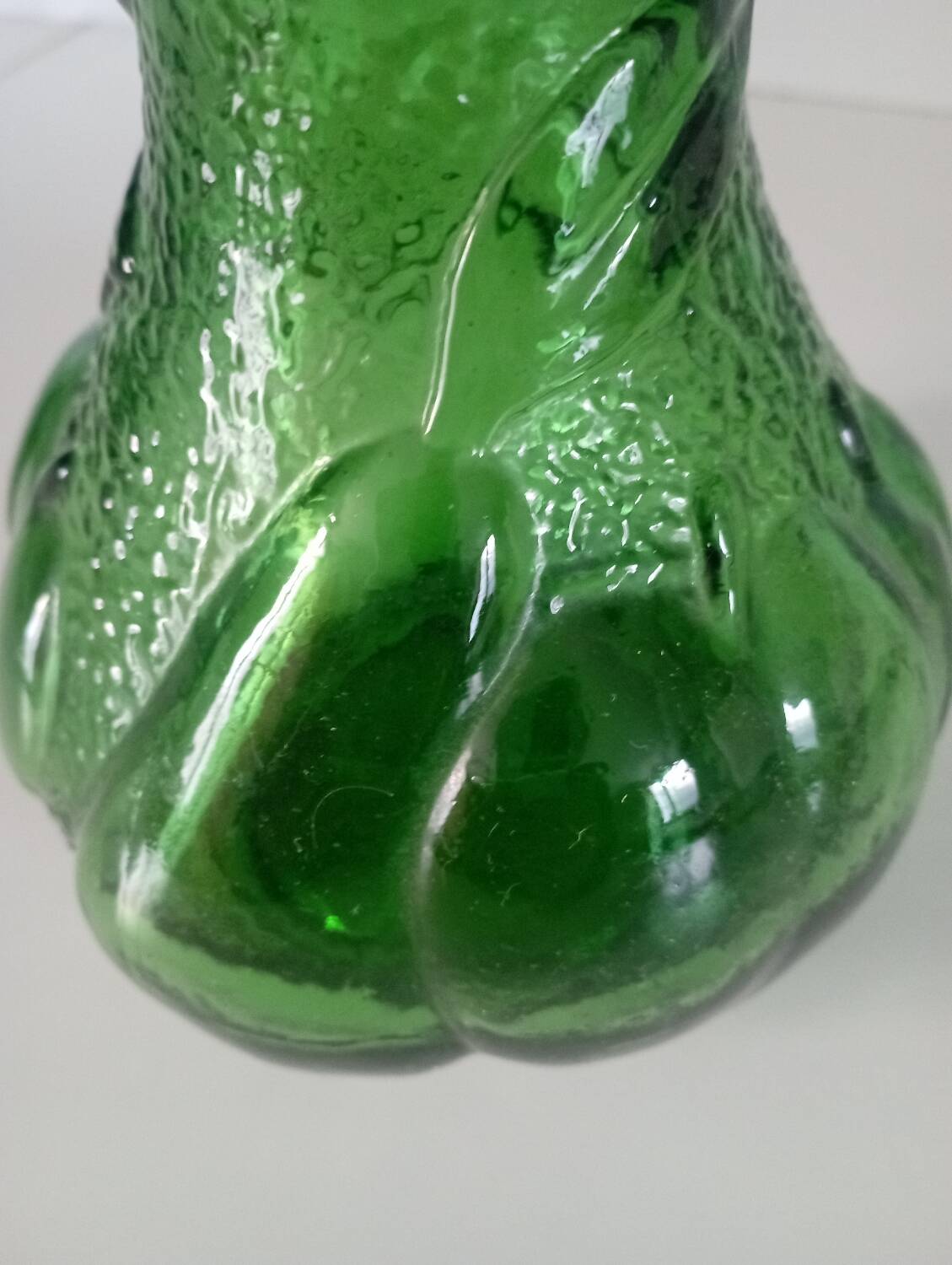 Green glass vase decorated with bunch of grapes and fruits