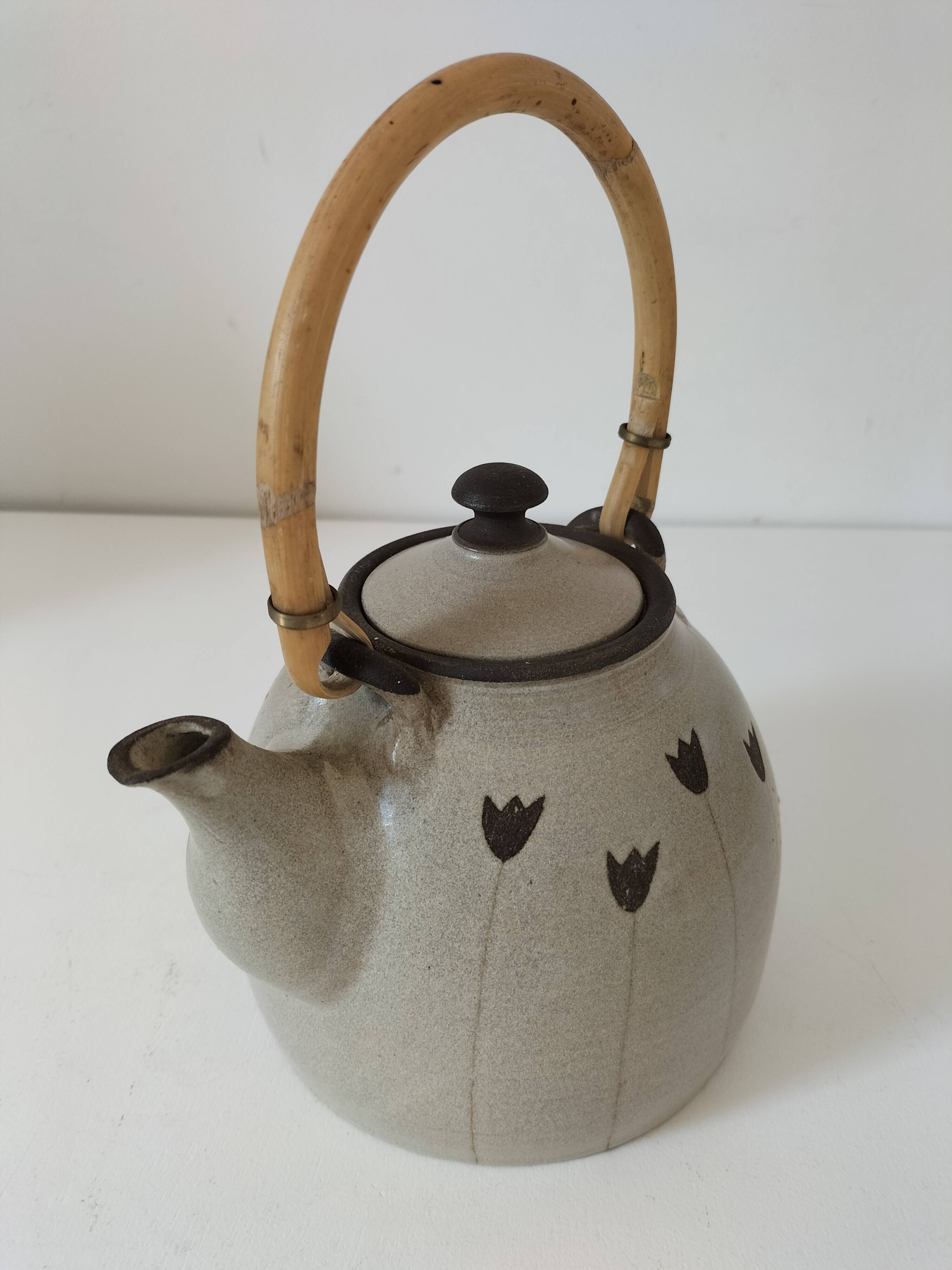 Beige stoneware teapot with stylized flowers and rattan handle