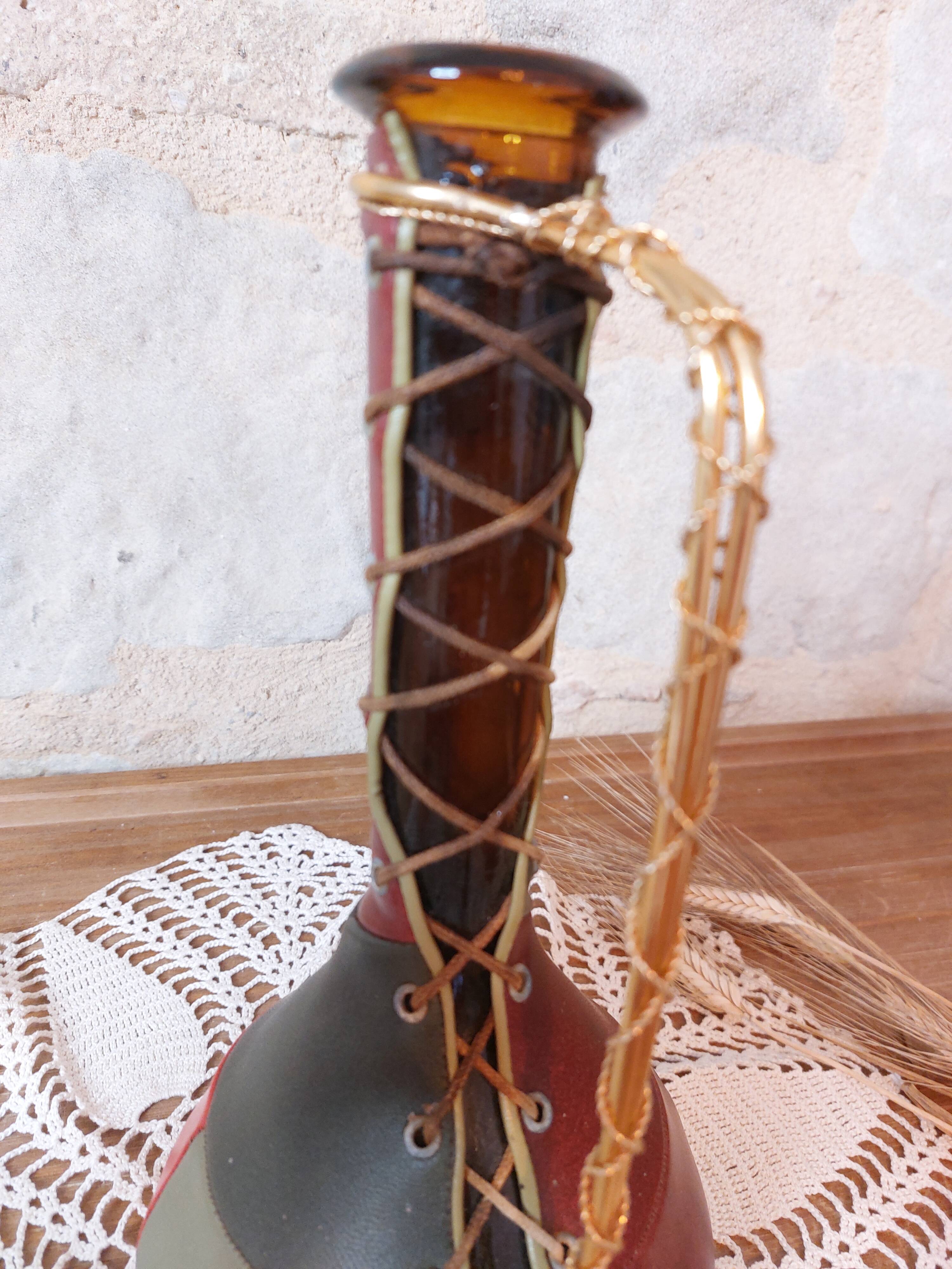 Amber bottle covered in colored leather with handle surrounded by wire, vintage