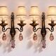 Maison Baguès, pair of wall sconces in wrought iron and gilded sheet metal, crystal pendants.