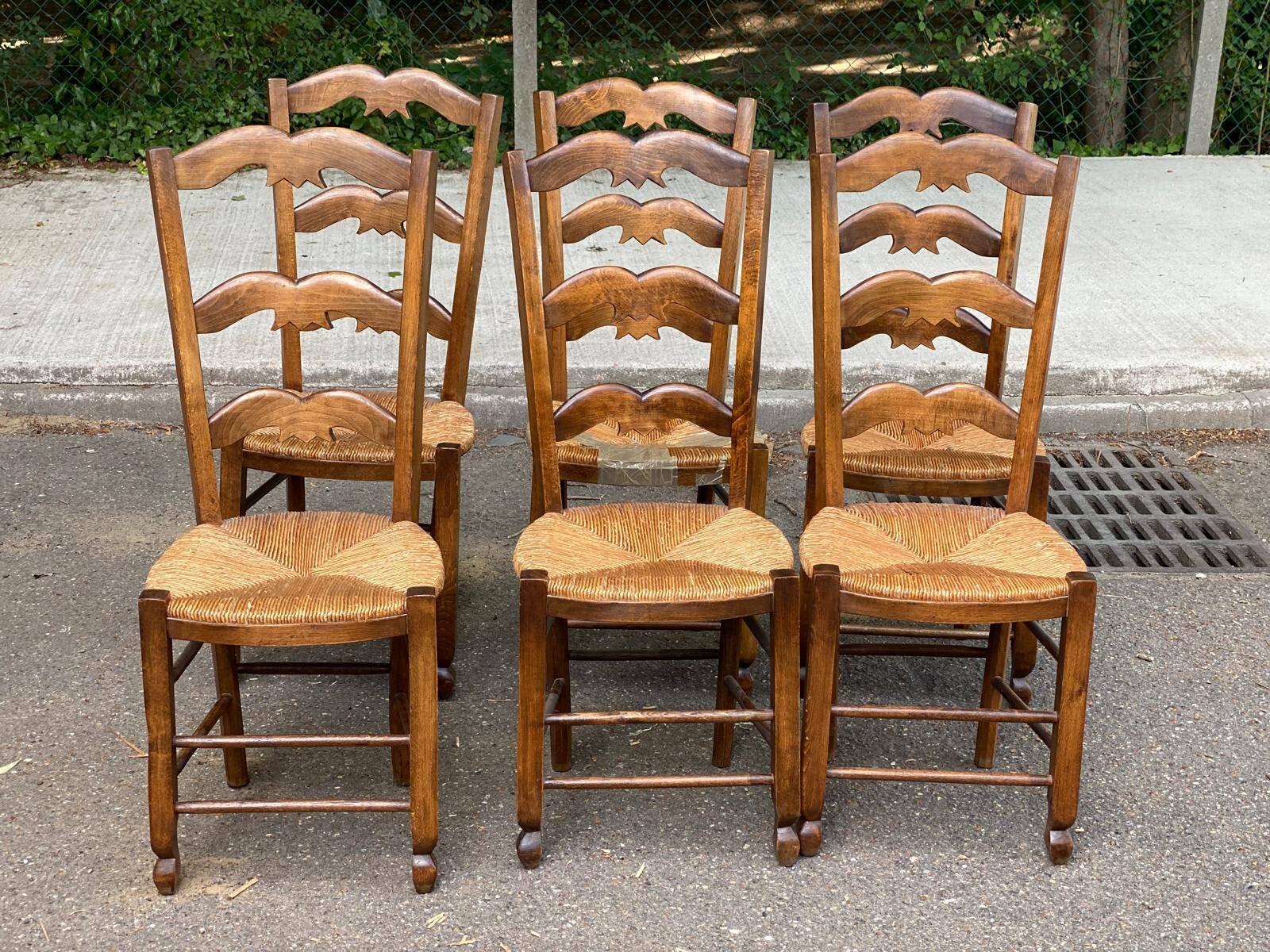 6 solid wood chairs with straw seats and butterfly carved backs.