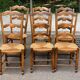 6 solid wood chairs with straw seats and butterfly carved backs.