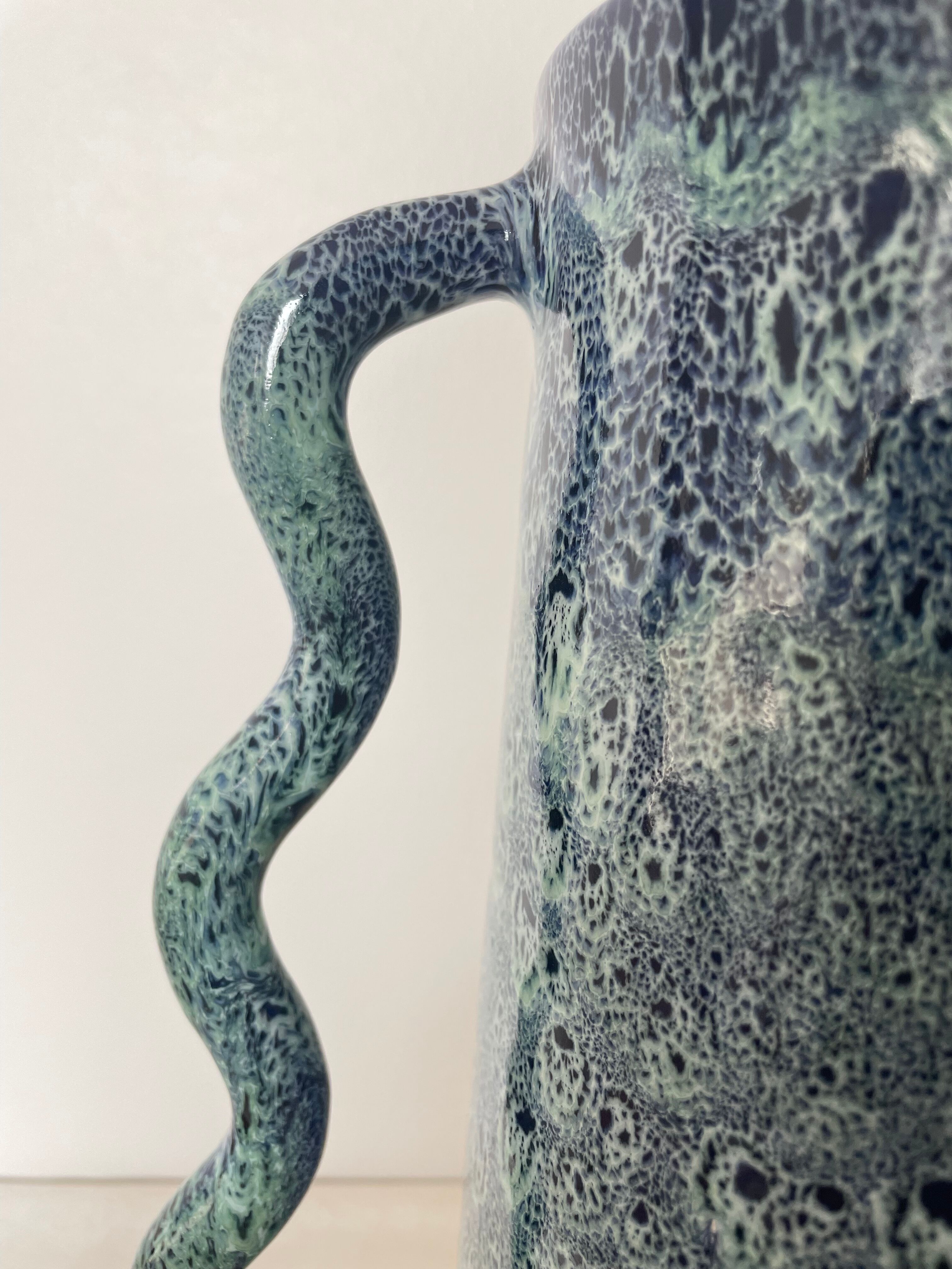 Blue-green ceramic vase with abstract wavy handles
