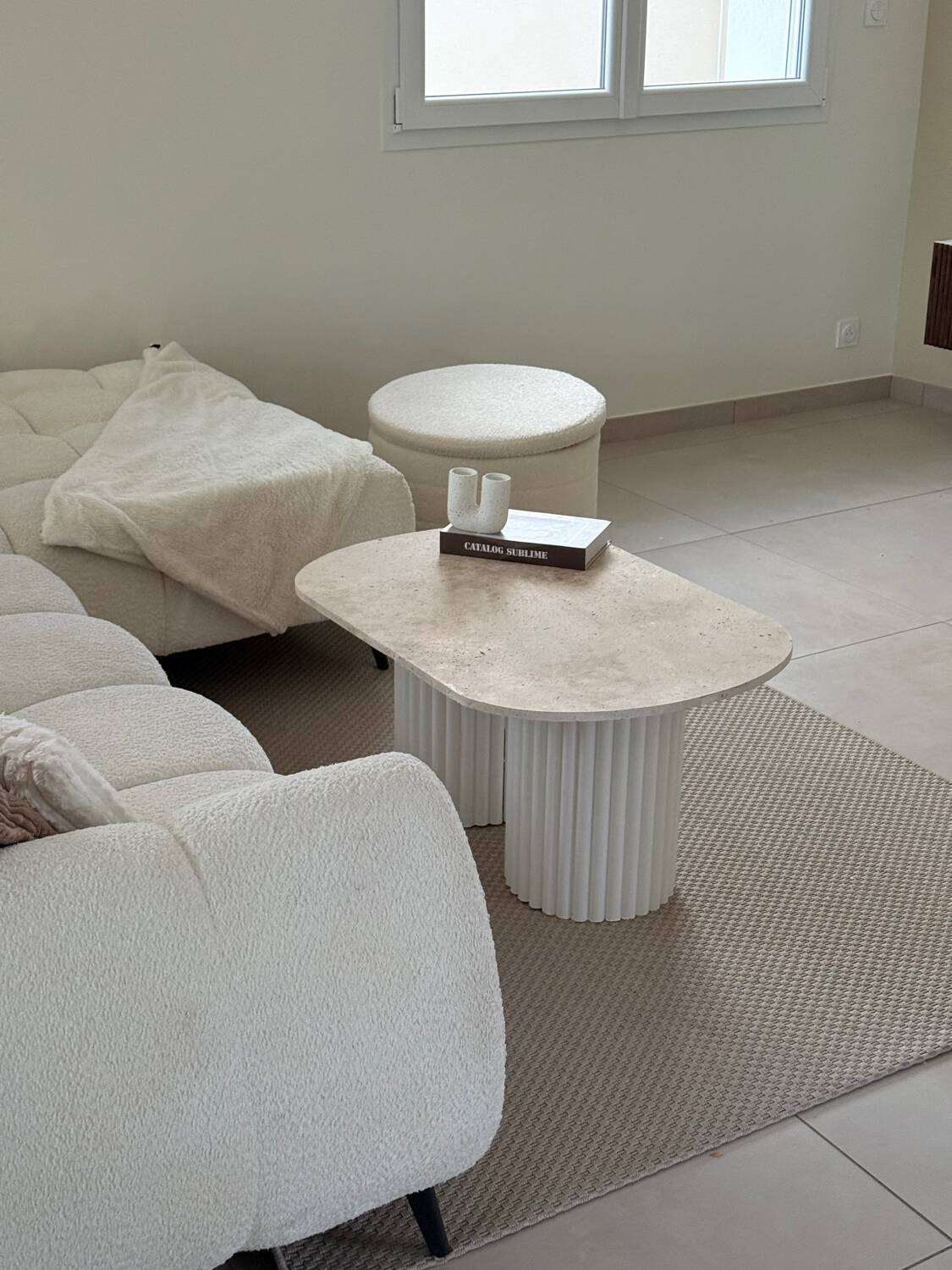 Oval coffee table in travertine and white fluted wood.