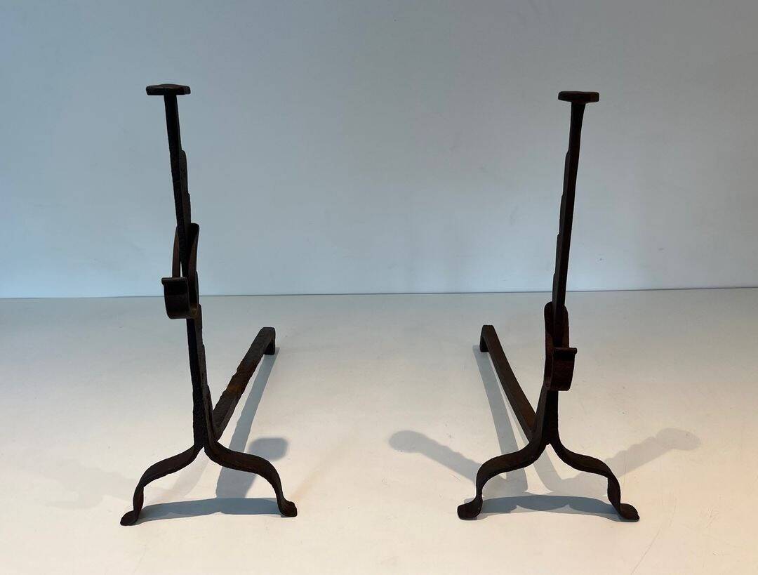Pair of wrought iron andirons with adjustable supports and tripod feet.