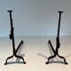 Pair of wrought iron andirons with adjustable supports and tripod feet.