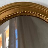 Oval-shaped wooden mirror in gold color