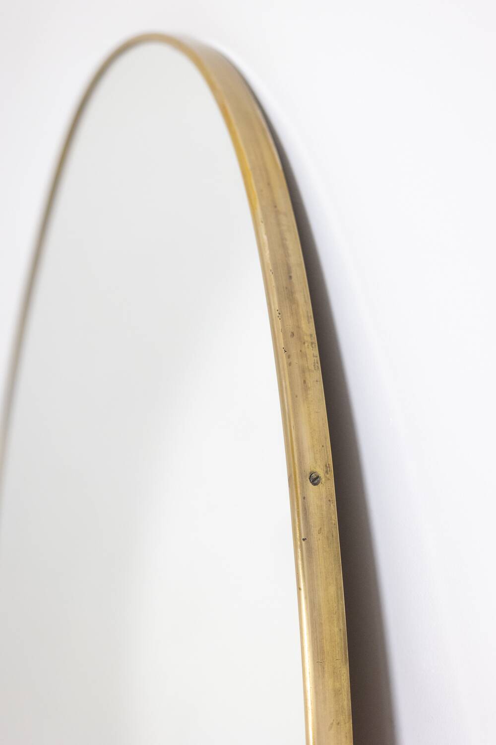 Oval shaped mirror set with a gilded brass rod. 1970s.