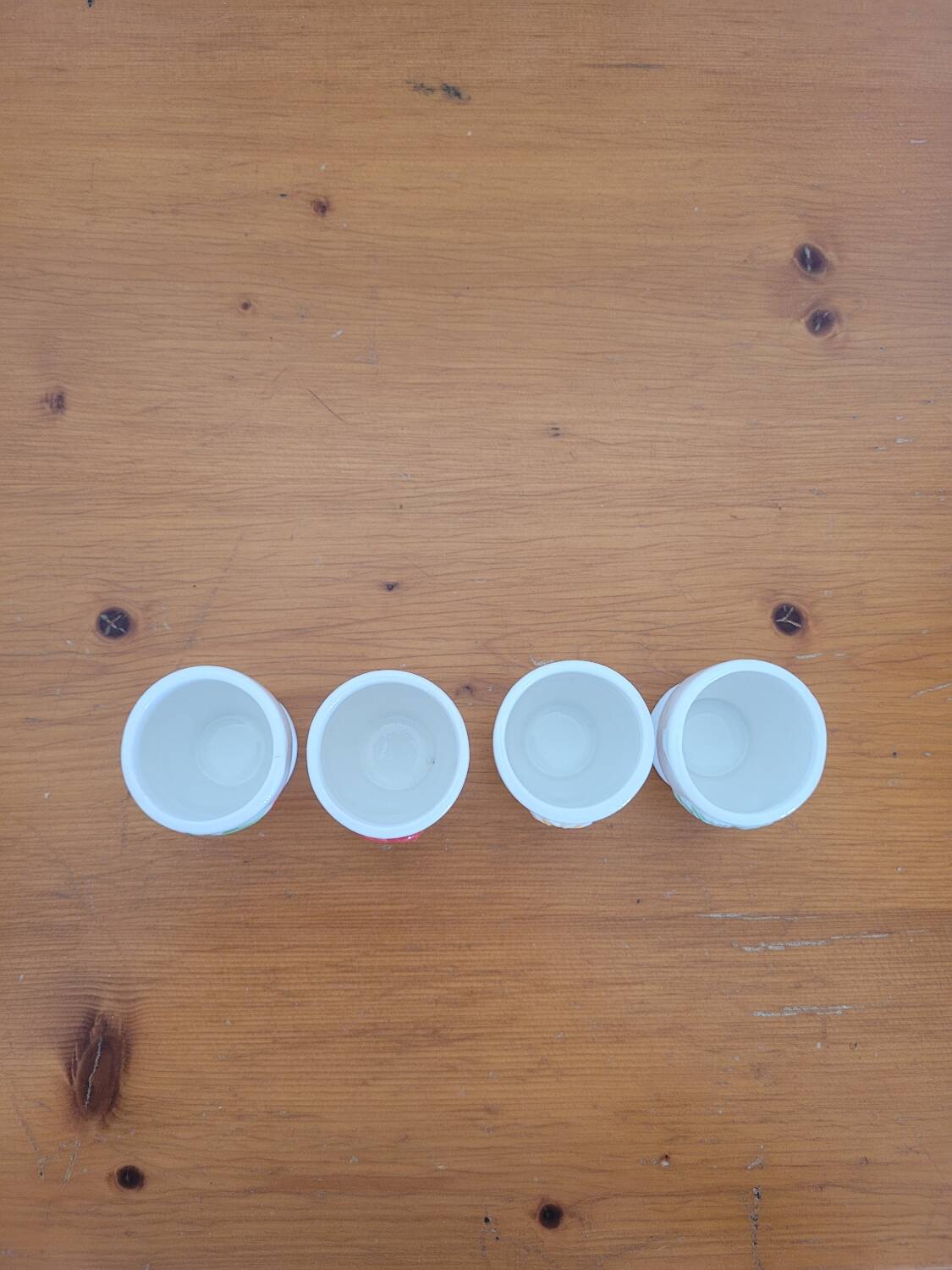 Set of four ceramic egg cups with a floral and fruit pattern.