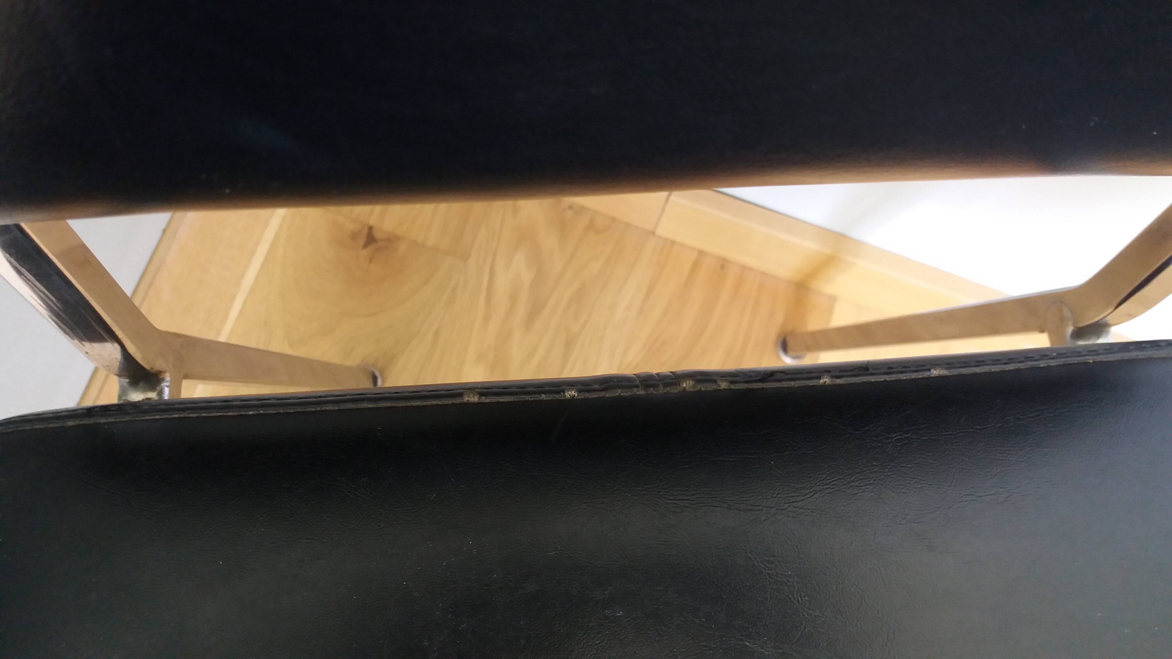 Chrome metal chairs and black faux leather upholstery in retro modernist style.