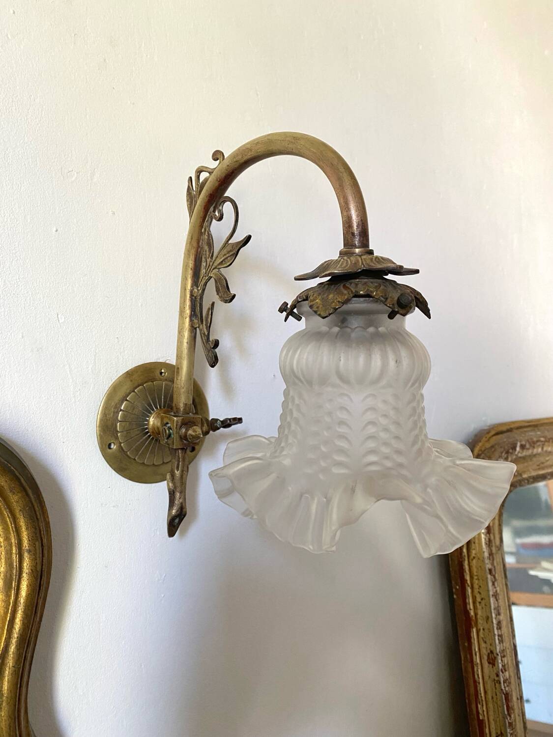 Antique brass wall light with glass shade.