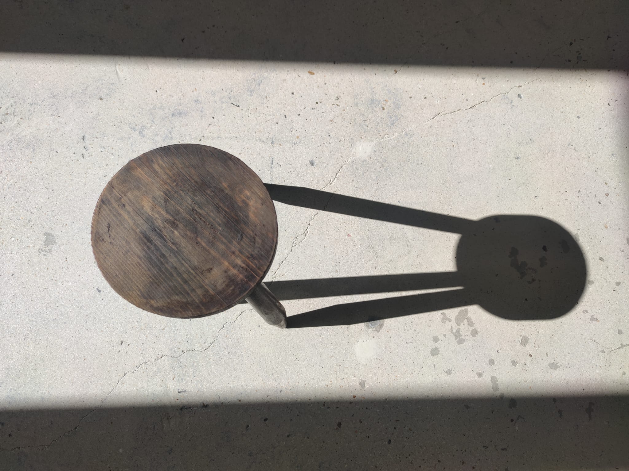Small brutalistic tripod stool in dark wood tapered feet circular seat
