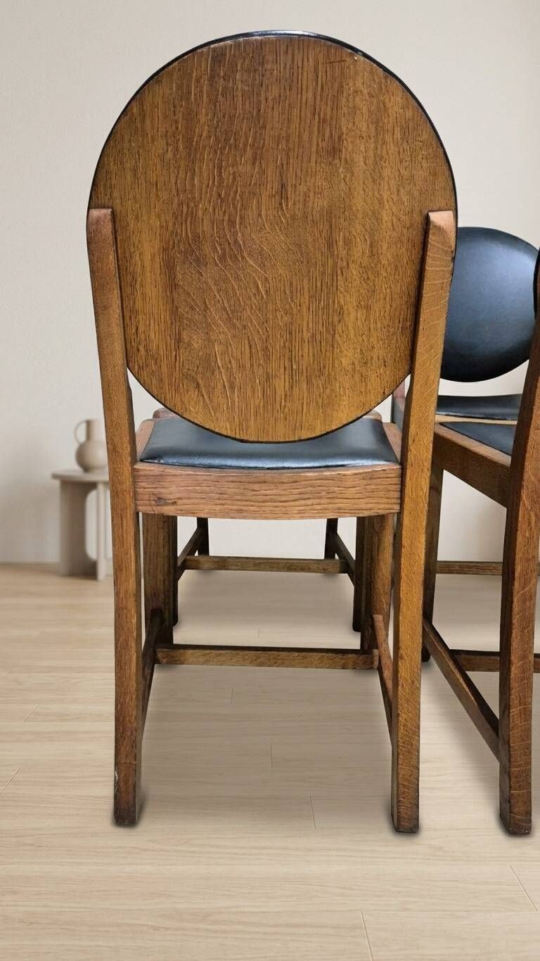 Set of four vintage wooden dining chairs with black leather upholstery