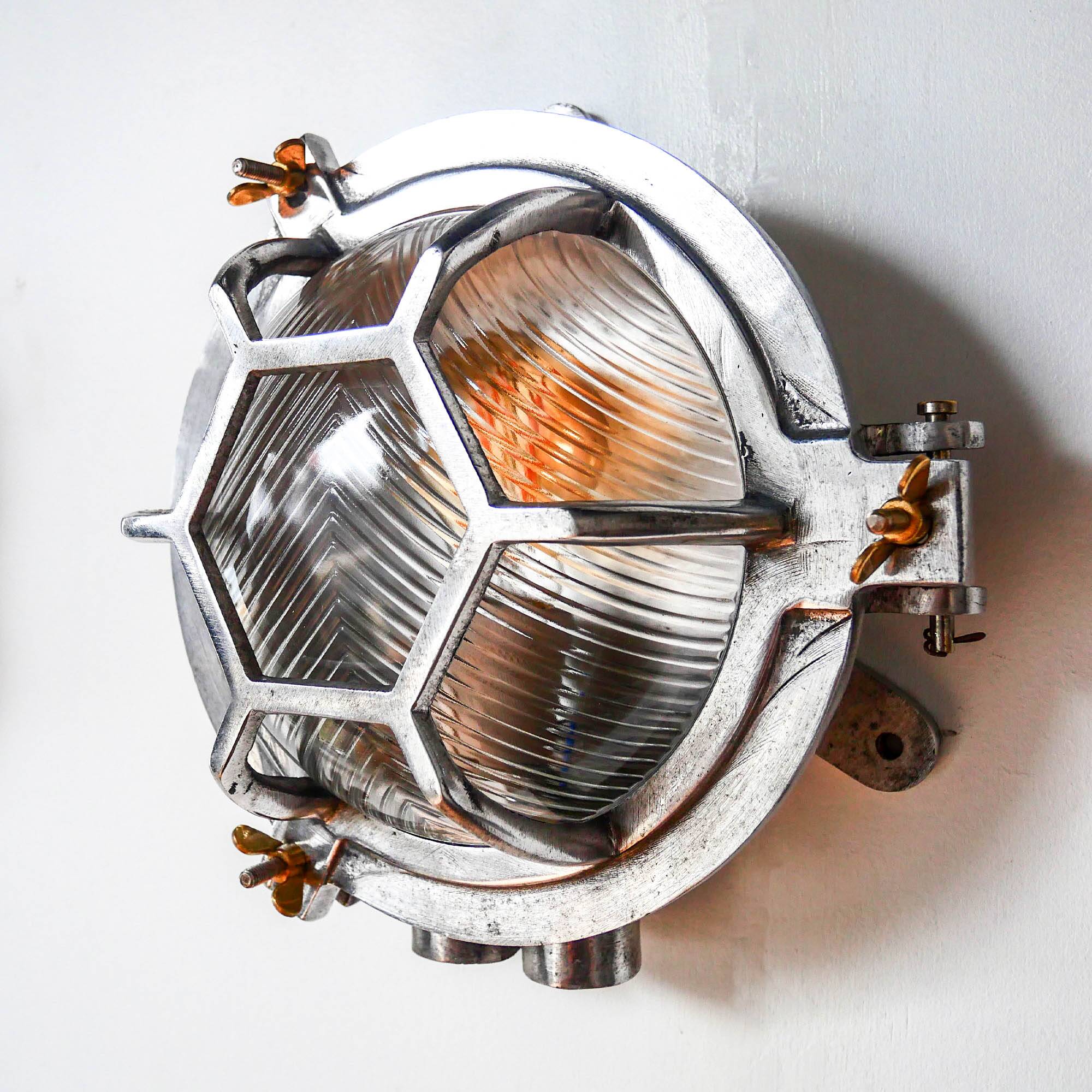 Old cast aluminum wall light with hexagonal grid and wide streaked glass.