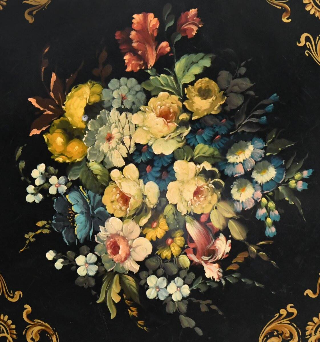 Blackened wooden side table decorated with a painted bouquet of flowers.