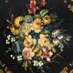 Blackened wooden side table decorated with a painted bouquet of flowers.