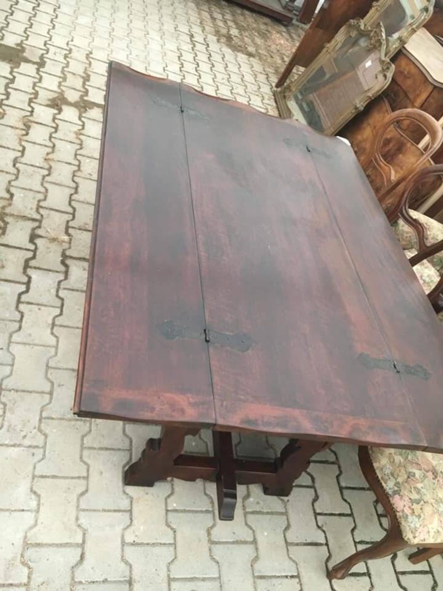 19th-century brown walnut dining table with sculpted trestle legs.