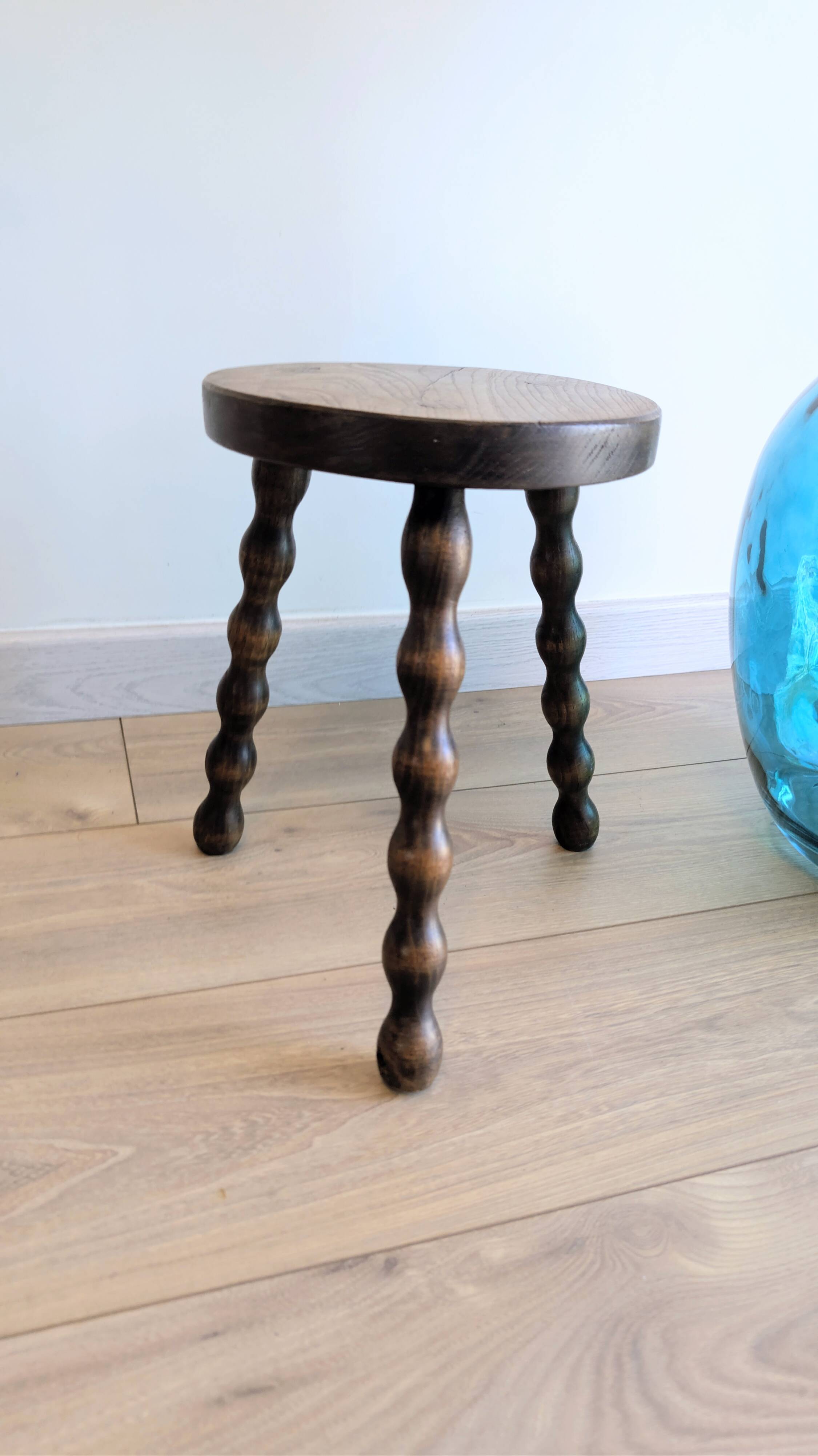 Small wooden tripod stool with turned legs, country style.