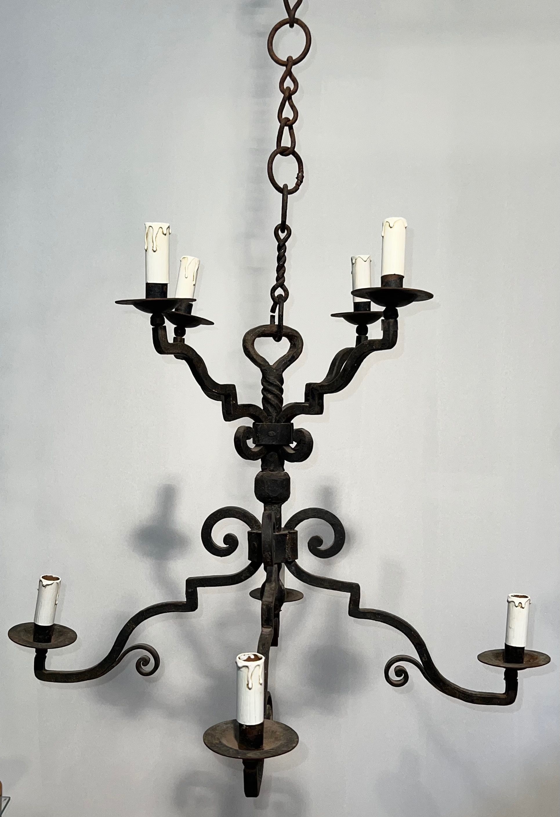 Two-tiered wrought iron chandelier with eight light arms in Gothic style.