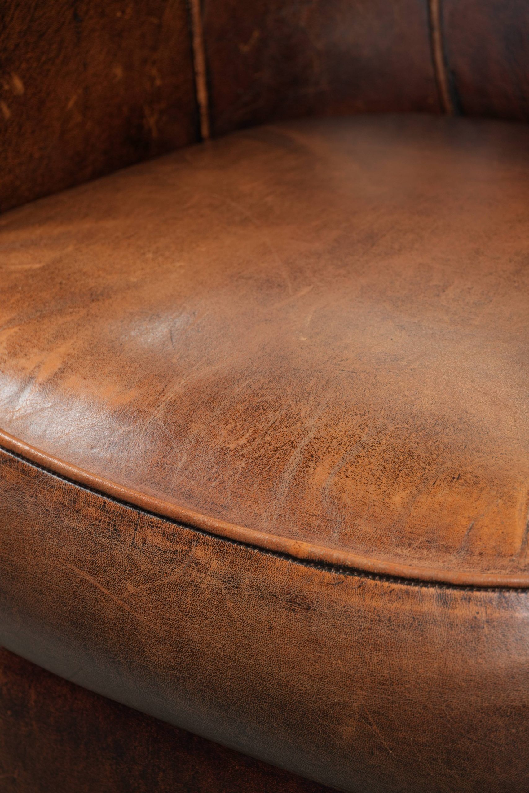 Fauteuil club en cuir de peau de mouton avec un coussin de siège fixe.