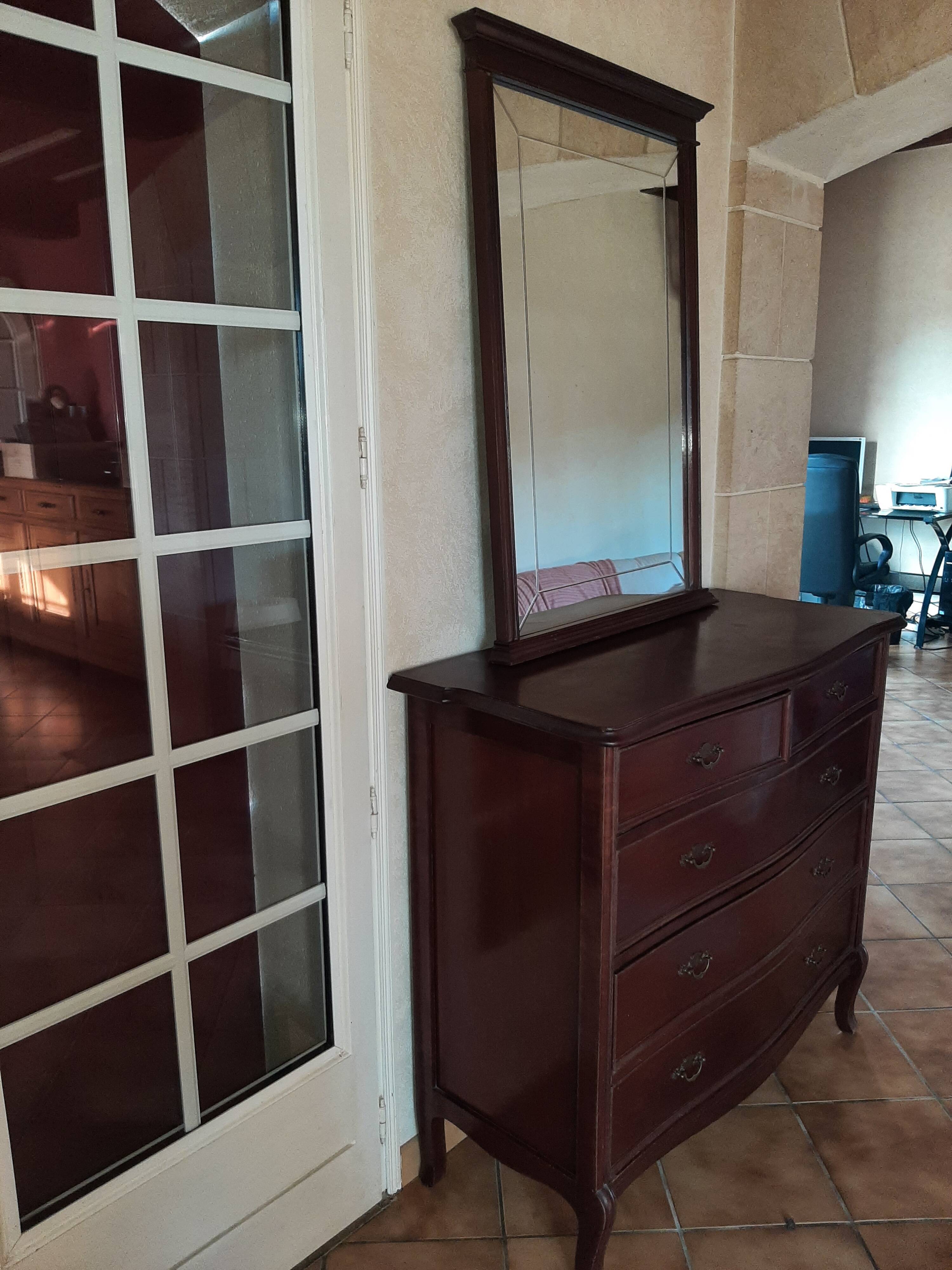 Style set: bevelled mirror and curved wooden chest of drawers.