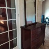 Style set: bevelled mirror and curved wooden chest of drawers.