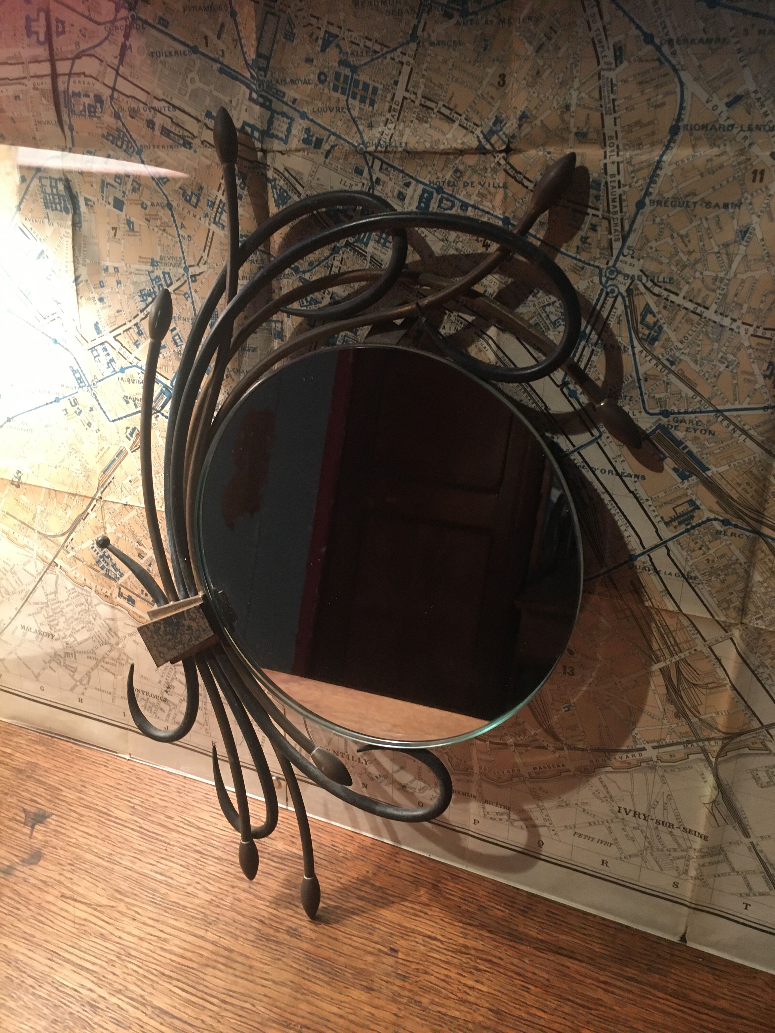 Round mirror surrounded by art deco style metal plants