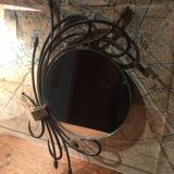 Round mirror surrounded by art deco style metal plants