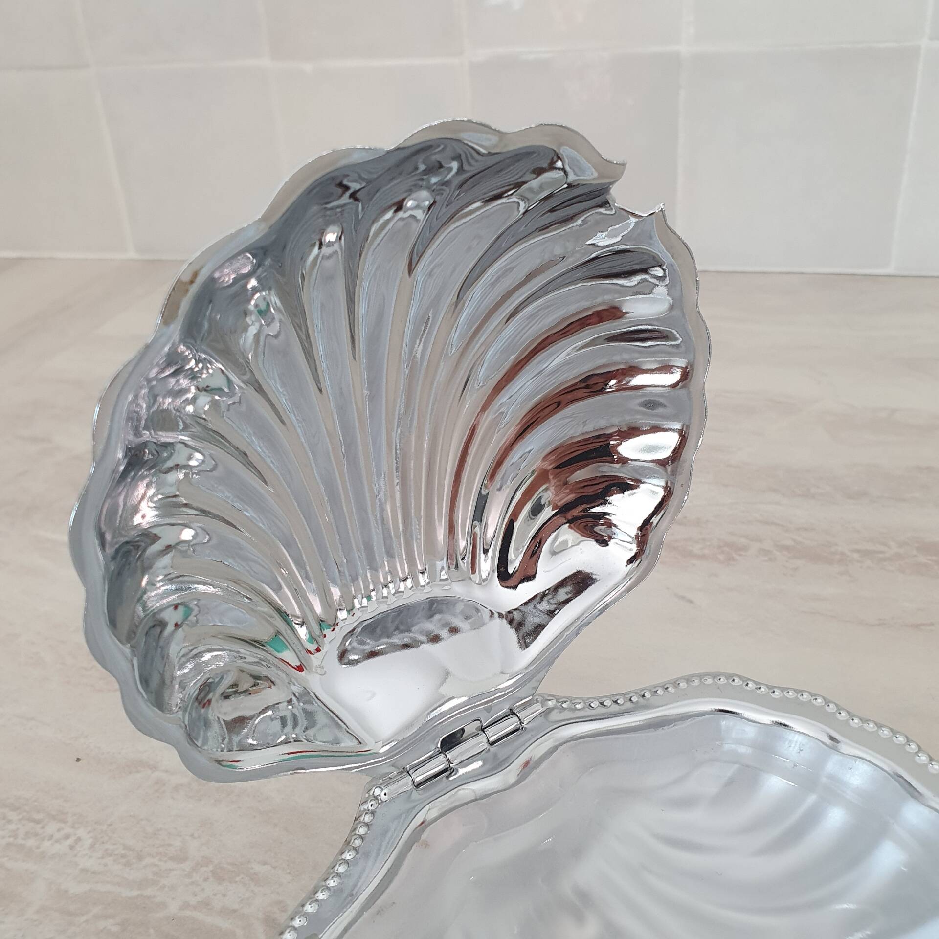 Shell-shaped butter dish in stainless steel and white glass bowl.