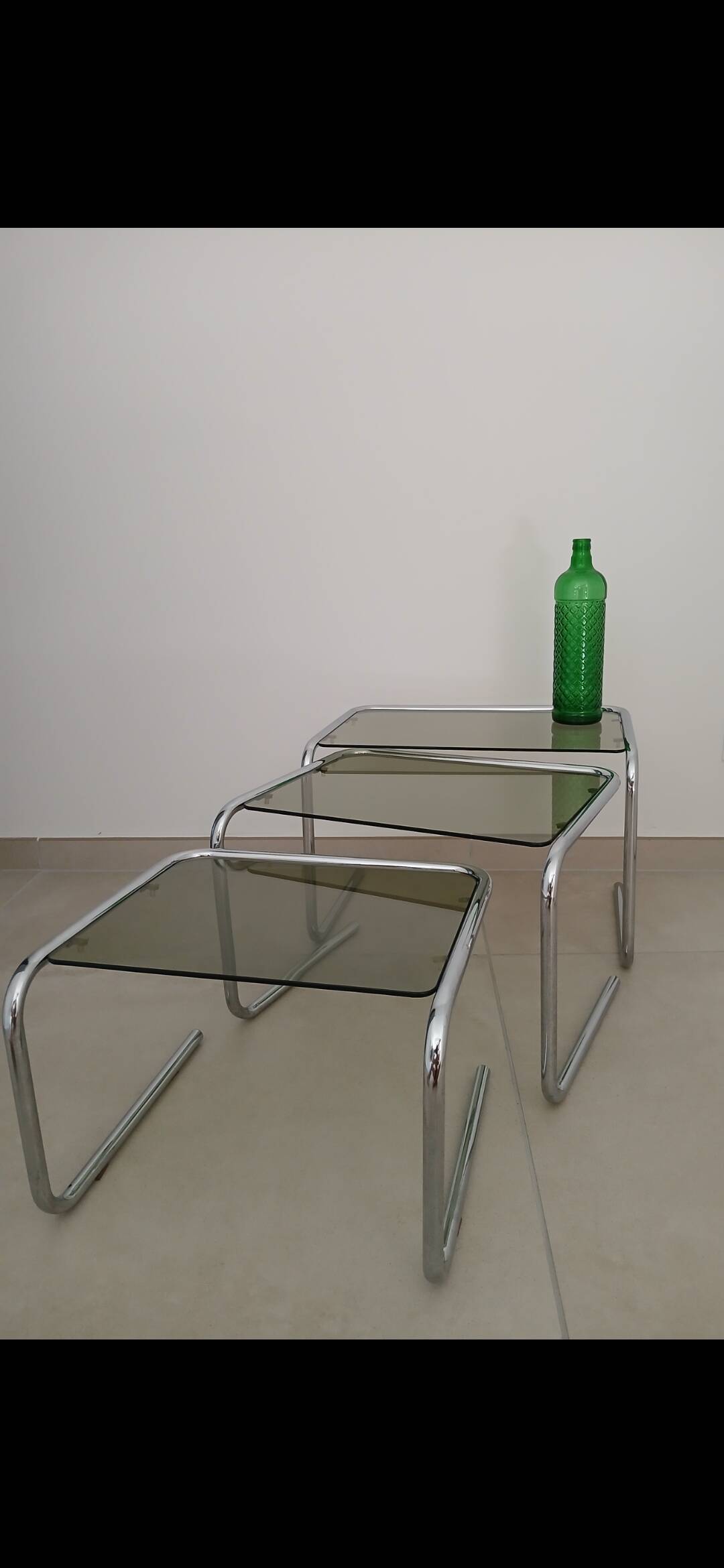 Nest tables in chrome metal and tinted glass.