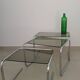 Nest tables in chrome metal and tinted glass.
