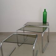 Nest tables in chrome metal and tinted glass.