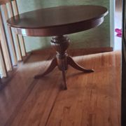 Round solid walnut table with central leg from the 1950s with extensions.