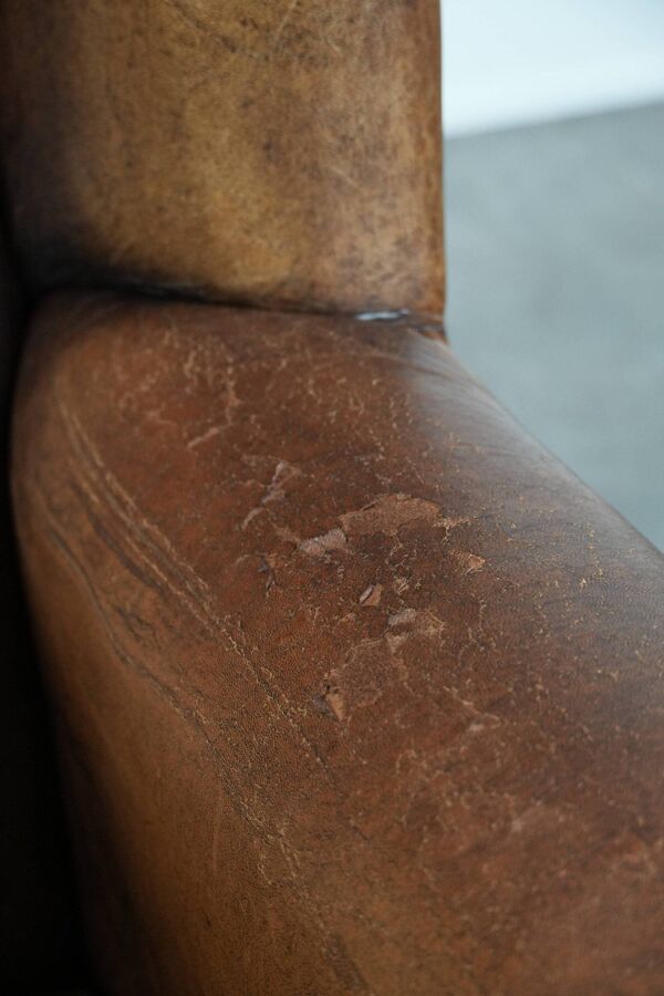Grand et confortable fauteuil en cuir de mouton avec des passepoils noirs.