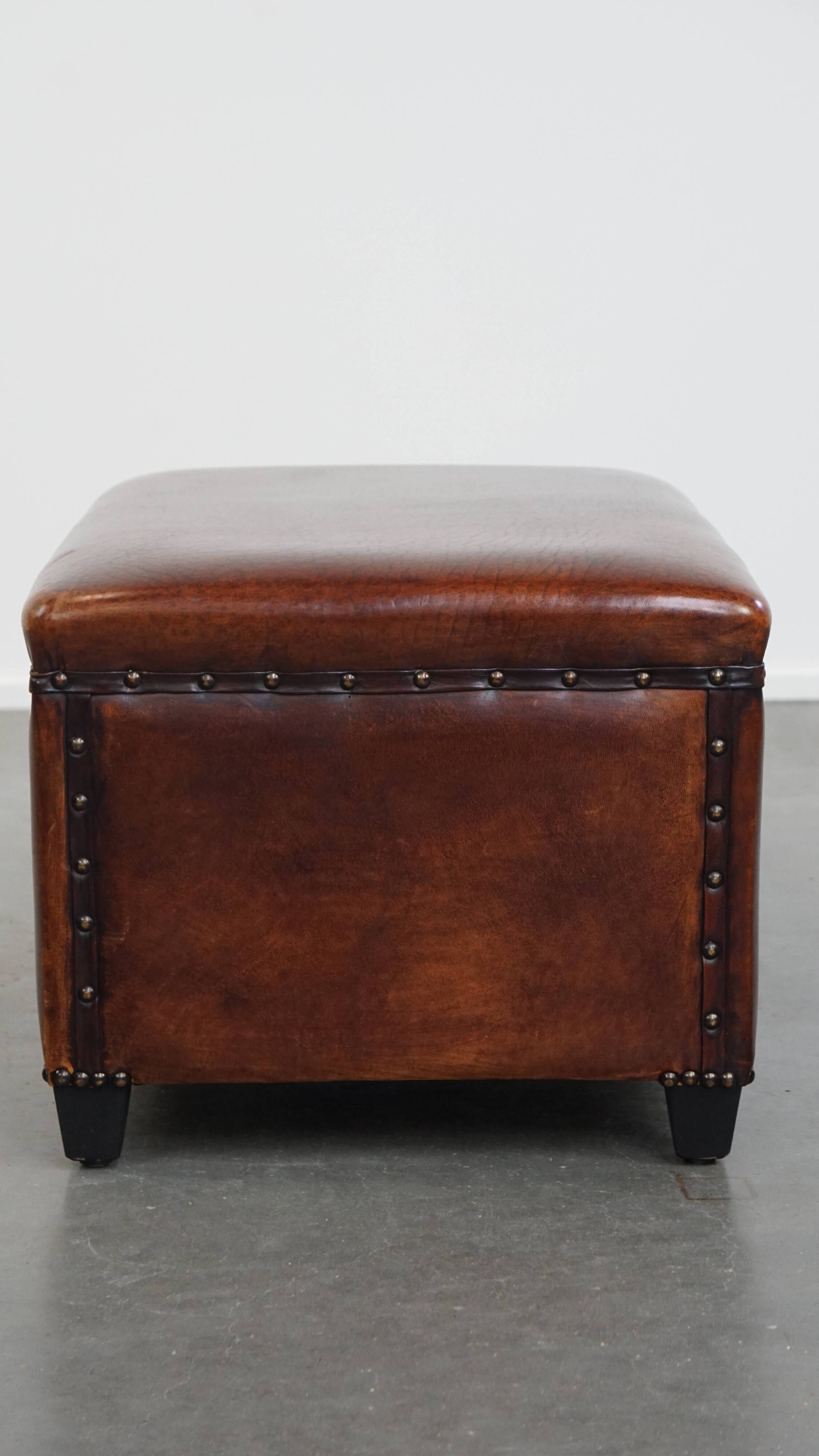 Cognac-colored sheepskin stool with decorative studs