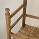 Old wooden high chair for children with a straw seat.
