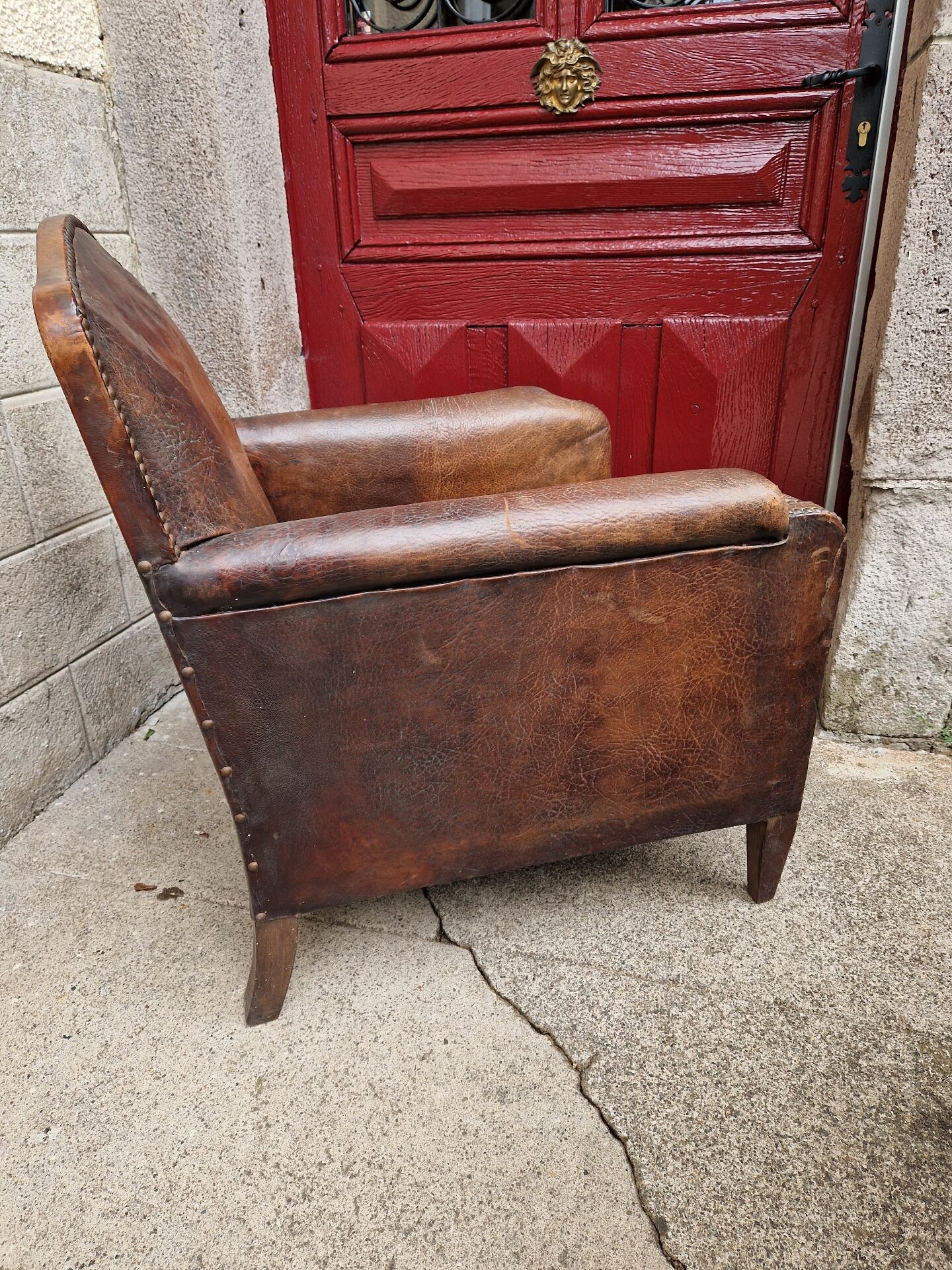 Antique club chair in patinated brown leather, early 20th century English style.