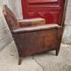 Antique club chair in patinated brown leather, early 20th century English style.