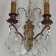 Pair of French antique brass double wall lights with assorted crystals.