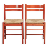 Ensemble de deux chaises en bois vintage rouges des années 1970 avec des sièges en rotin tressé.
