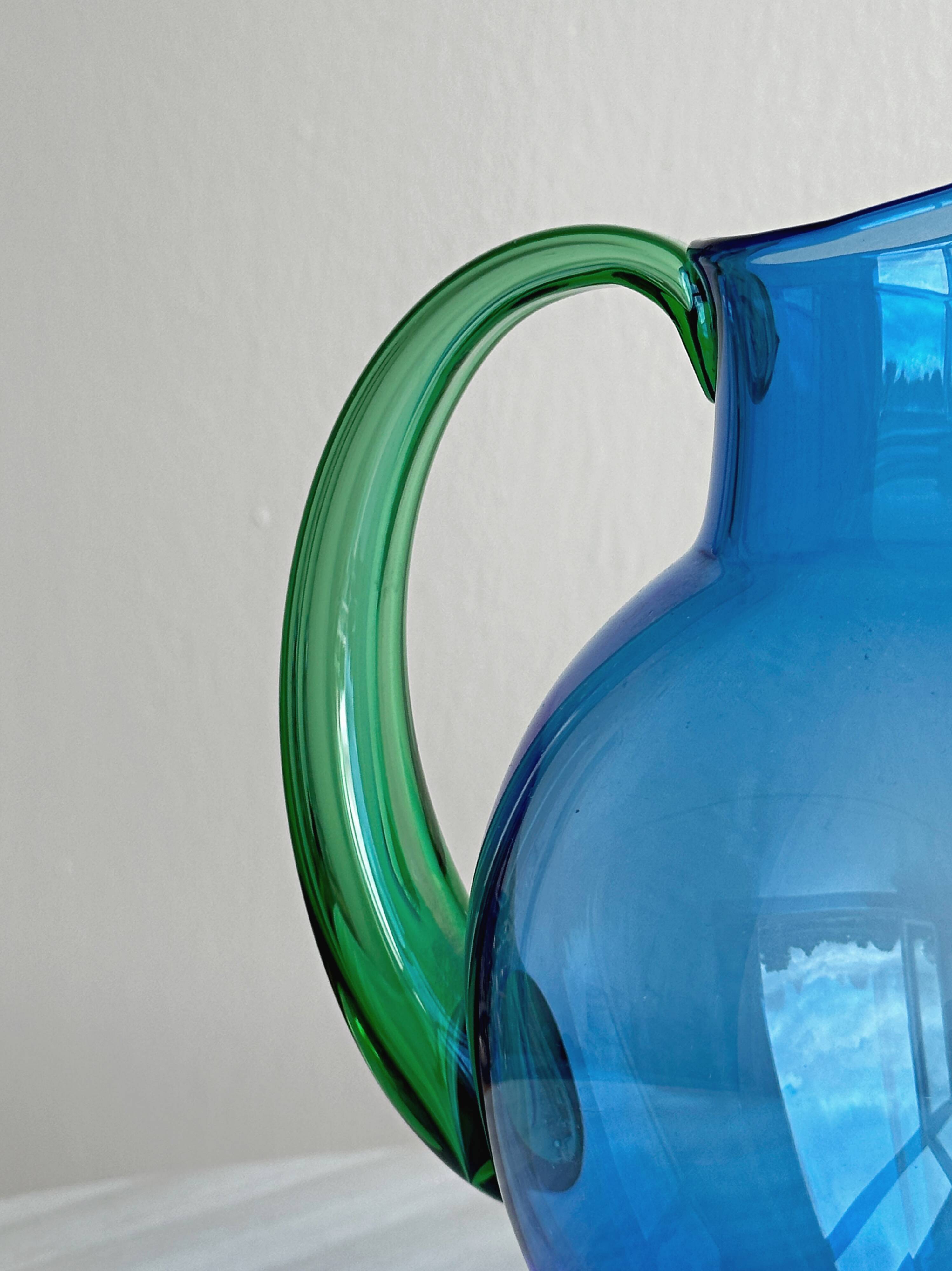 Translucent blue glass jug with a green handle.