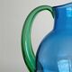 Translucent blue glass jug with a green handle.