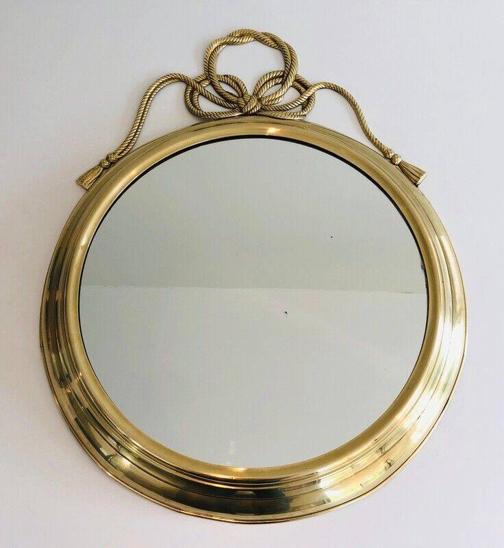 Large decorative oval mirror in brass adorned with a significant twisted bow.