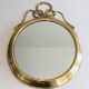 Large decorative oval mirror in brass adorned with a significant twisted bow.