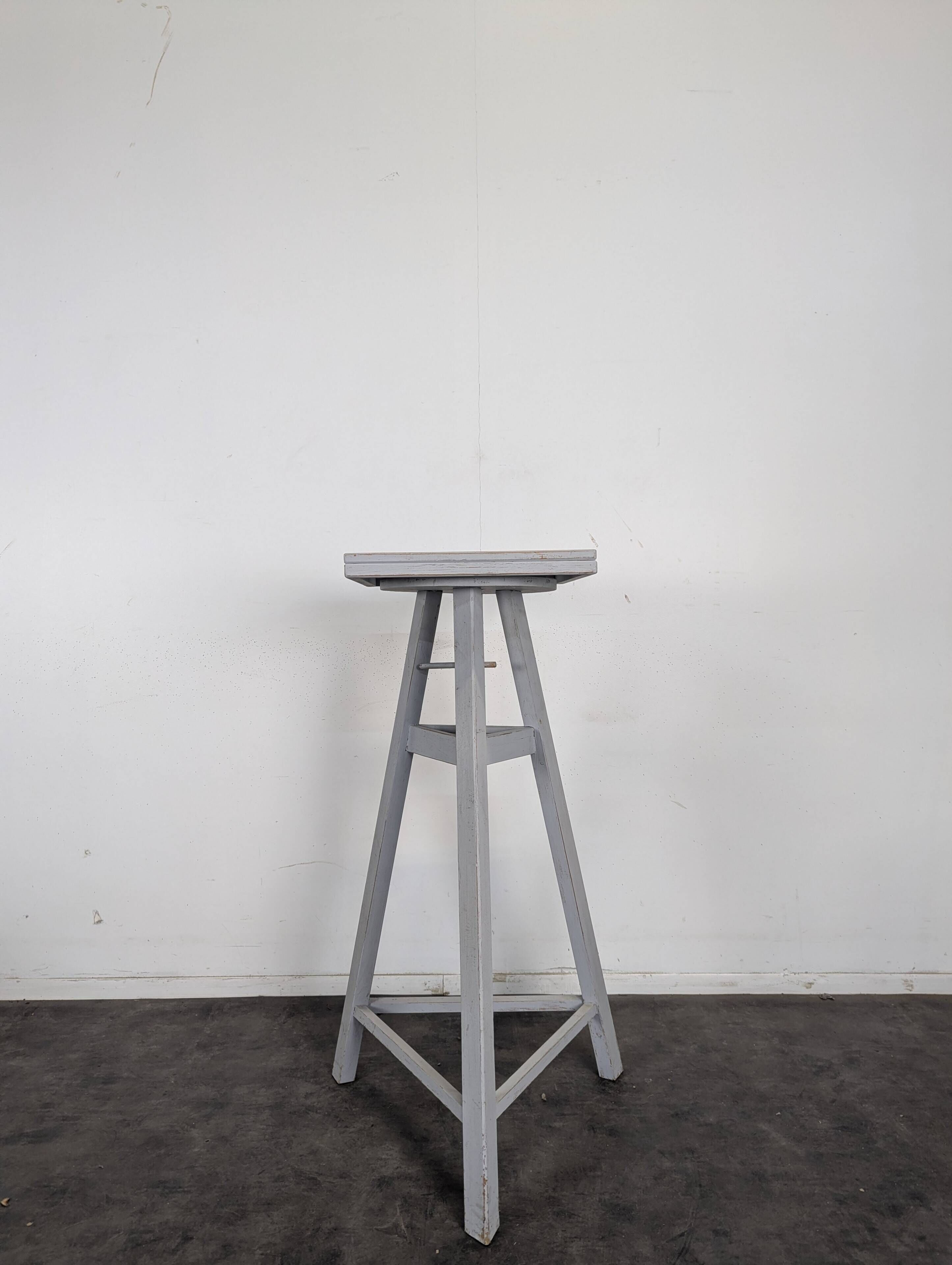 Tripod sculptor's stool in grey painted wood with a rotating top.
