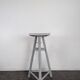 Tripod sculptor's stool in grey painted wood with a rotating top.